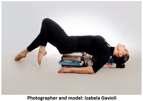 A dancer reclined over stacks of books