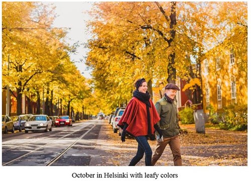 Two people walking down a street with autumn foliage